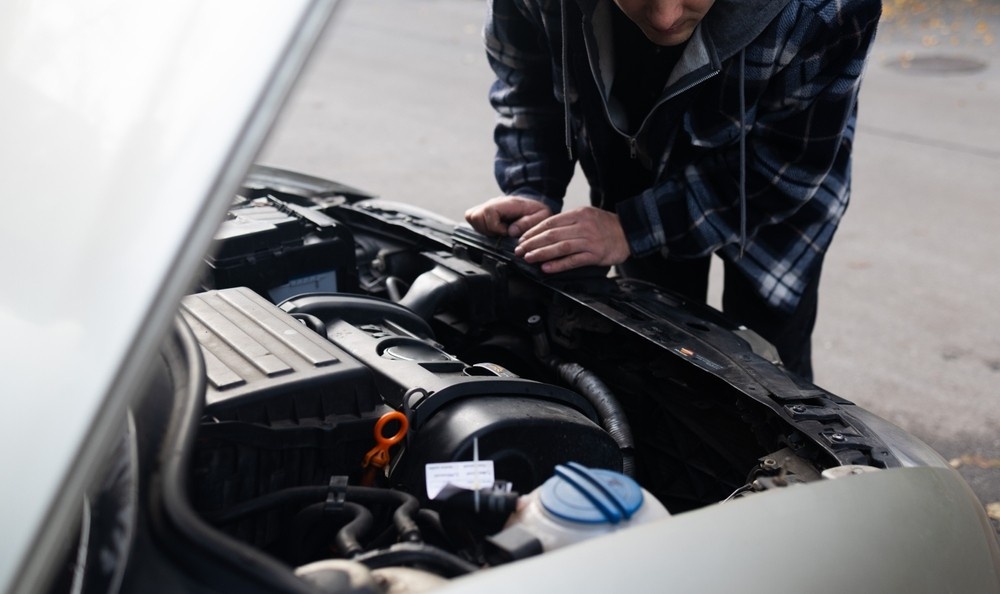 barbat care se uita sub capota masinii