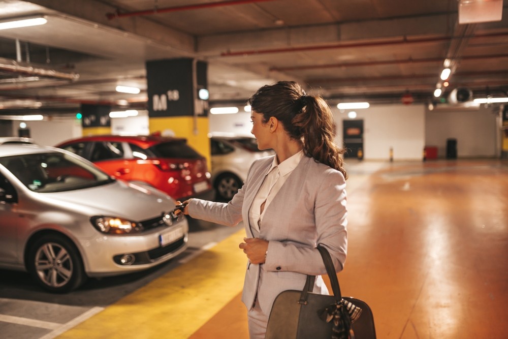 femeie care inchide masina parcata intr-o parcare subterana